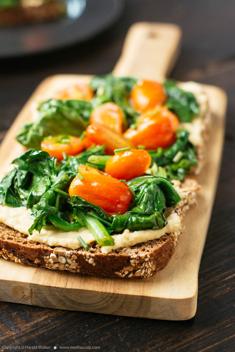 Stock photo of Hummus Toast with Spinach and Cherry Tomatoes