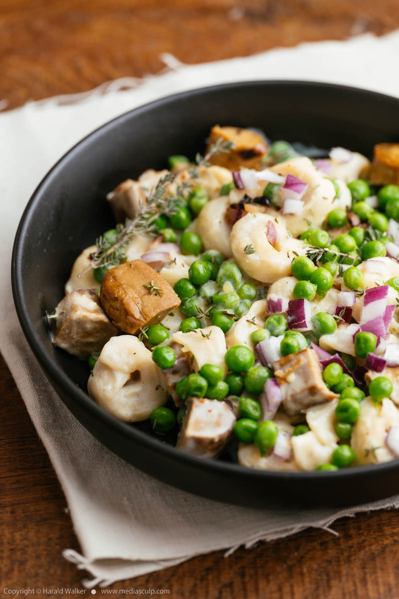 Stock photo of Tortellini with peas and Vegan Sausages